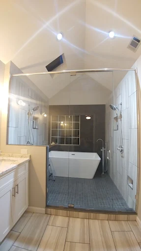Frameless glass shower beside a freestanding tub